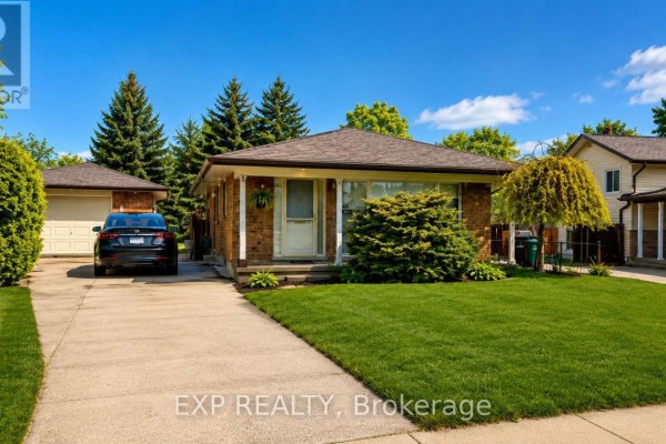 Wide shot of the brick bungalow's front facade, driveway, and garage. - 76 Appalachian Crescent, Kitchener