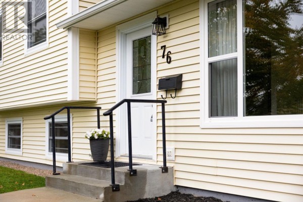 Close-up of the front door with a glass insert, black mailbox, and white potted flowers on the steps. - 76 Appletree Lane, Kentville