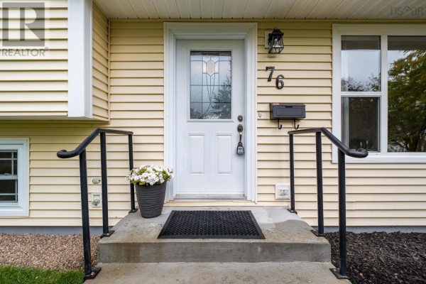 Entrance to the cream-colored house featuring a white door with a glass insert and black railings. - 76 Appletree Lane, Kentville