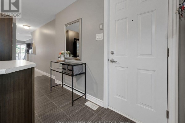 Entranceway of a townhouse with a white door, grey walls, and tiled floor. - 76 Argent Private, Ottawa
