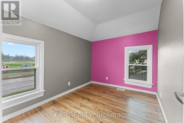 Room with hardwood floors, pitched ceiling, and pink accent wall - 76 Bell Street Port Colborne