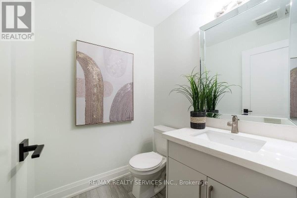 Powder room with light green walls, a vanity with a white countertop, and a large mirror. - 76 Burton Street, Hamilton