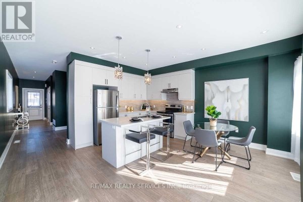 Open concept kitchen and dining area with white cabinets, stainless steel appliances, and a glass-top dining table. - 76 Burton Street, Hamilton