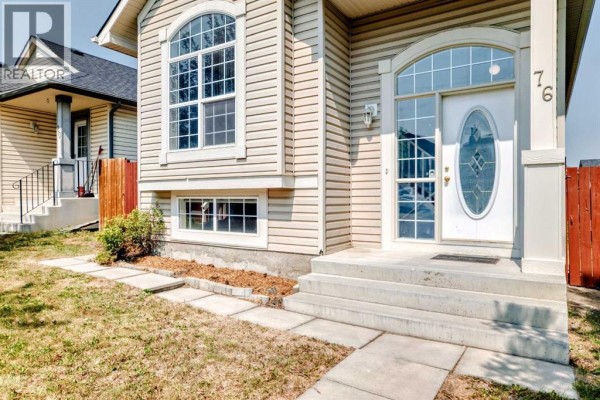 Close-up view of the beige house entrance with a white door and arched window. - 76 Coville Close Ne, Calgary