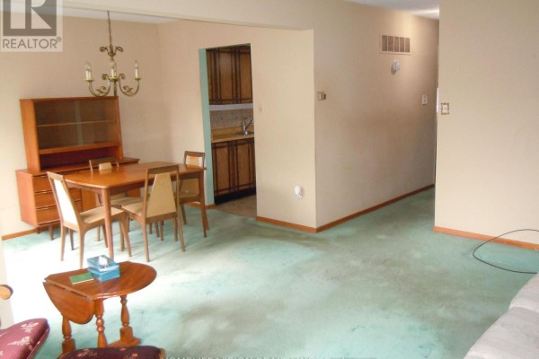 Living and dining room area with a wooden hutch, dining table, and green carpet. - 76 Crayford Drive, Toronto