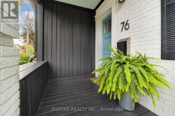 View of the dark wood porch with a seating area and a potted fern near the blue door. - 76 Hiltz Avenue, Toronto