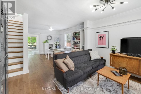 Living room with grey sofa, wooden coffee table, and dining area visible in the background. - 76 Hiltz Avenue, Toronto