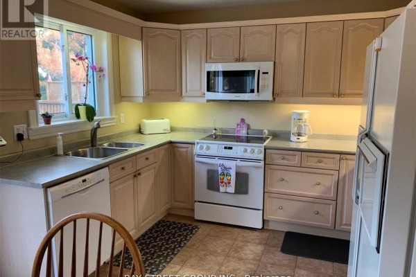 Corner kitchen with light wood cabinets, white appliances, and a window. - 76 Mayfair Drive, Barrie