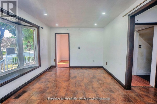 Interior living room with a bay window, wood-look flooring, and an open doorway. - 76 Mccaul Street, Brampton