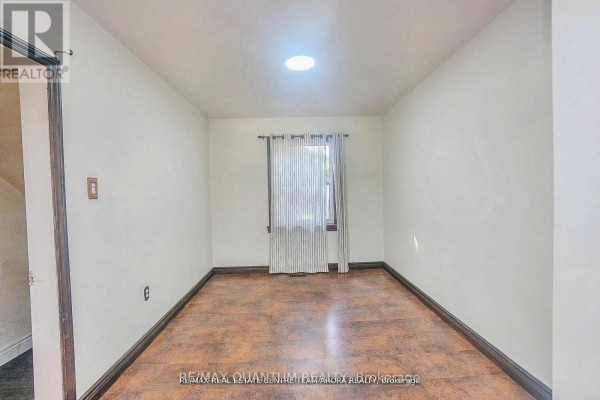 Interior room with white walls, a single window with curtains, and wood-look flooring. - 76 Mccaul Street, Brampton