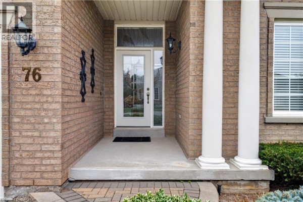 Close-up of the front entrance with a glass-paneled door and two ornate black wall sconces. - 76 Mcdermott Trail, Stouffville