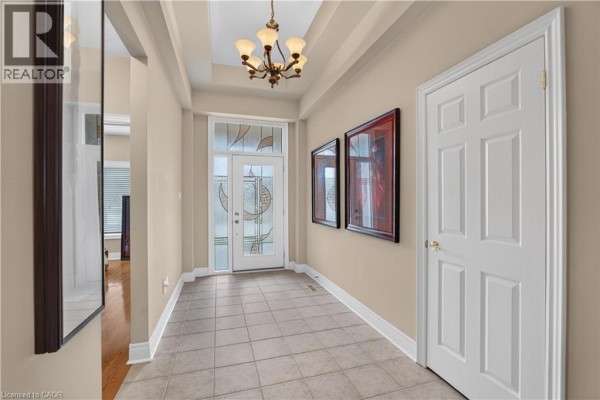 Interior foyer with beige walls, tiled floor, glass-paned door, and a decorative chandelier. - 76 Mcdermott Trail, Stouffville