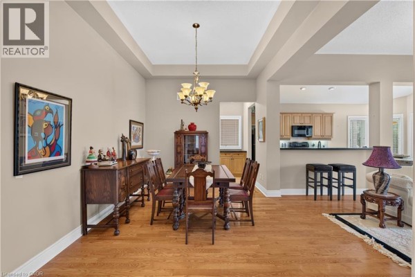 Dining area with a wooden table, buffet, china cabinet, and view into the kitchen and living area. - 76 Mcdermott Trail, Stouffville