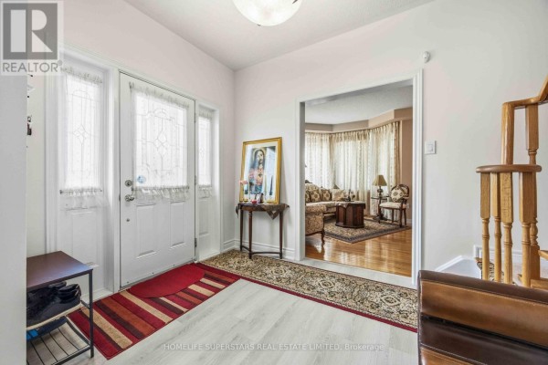 Entrance foyer with white double doors, red and striped rugs, and view into a living room. - 76 Riverlands Avenue, Markham