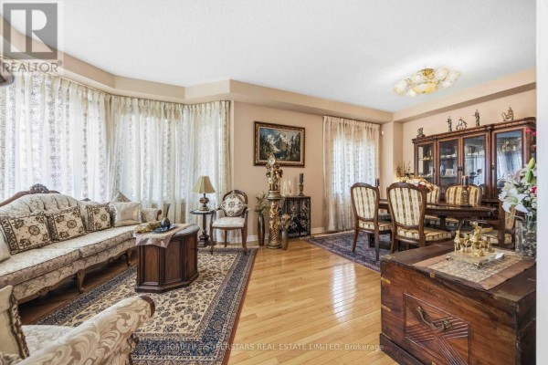 Living and dining room with light wood floors, ornate furniture, patterned rugs, and large bay windows. - 76 Riverlands Avenue, Markham