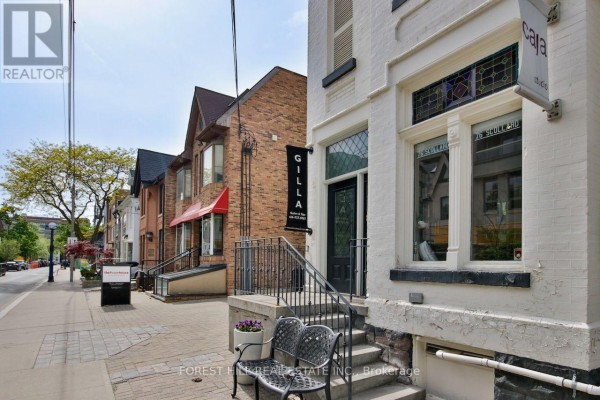Interior hallway with view of stairs and open doorway to a salon space with chairs. - 76 Scollard Street, Toronto