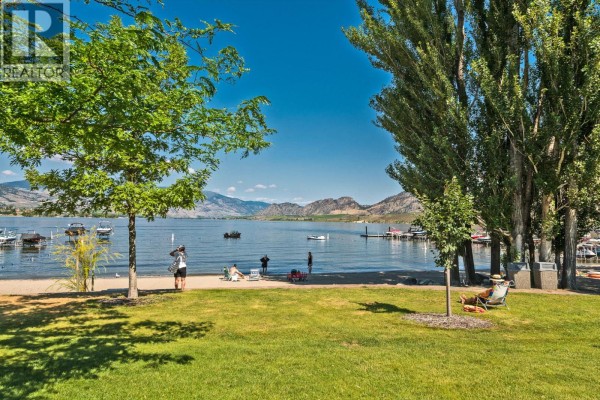 Lush green lawn and trees with Osoyoos lake and mountains in the background. - 7600 Cottonwood Drive Unit# 425, Osoyoos
