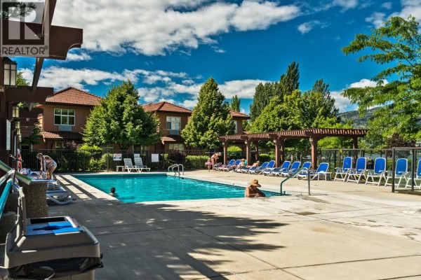 An outdoor swimming pool and hot tub with lounge chairs and buildings in the background. - 7600 Cottonwood Drive Unit# 425, Osoyoos
