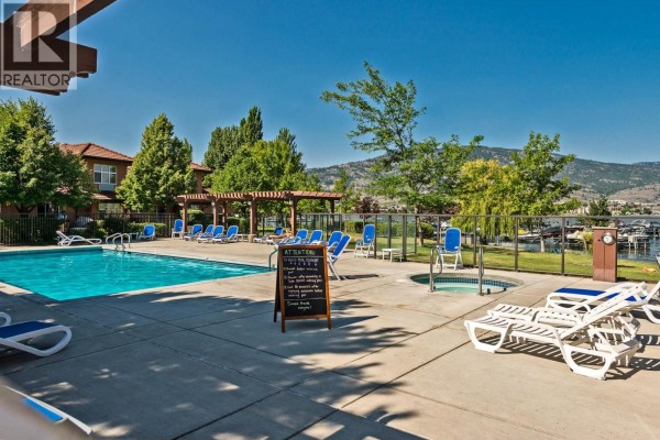 Outdoor swimming pool and hot tub area with lounge chairs, pergolas, and a view of the lake and marina. - 7600 Cottonwood Drive Unit# 425, Osoyoos
