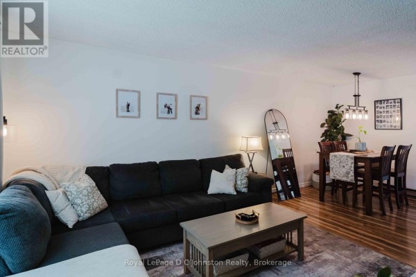 Living and dining area with a charcoal sectional sofa, wooden dining table, and hardwood floors. - 761 Arlington Street, Saugeen Shores