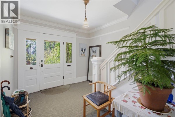 Interior entryway with carpet, white staircase, wooden chair, and large potted plant. - 761 E 15th Avenue, Vancouver