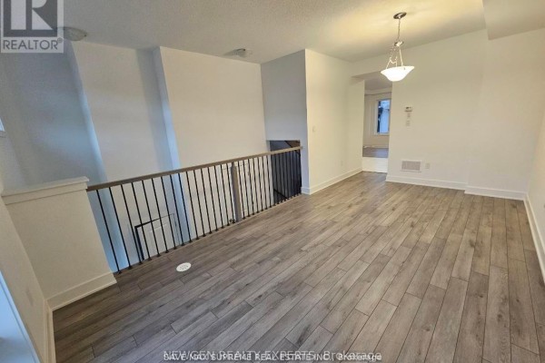 Open-concept living space with light wood floors, white walls, and a view of the staircase. - 763 Stanstead Path, Oshawa