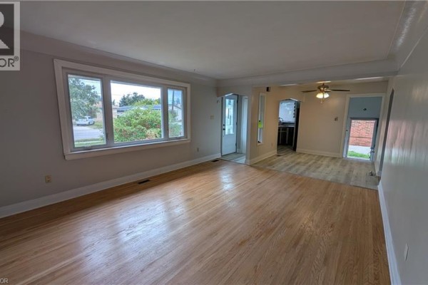 Living room with light grey walls, hardwood floors, and a large window overlooking the street. - 763 Upper Ottawa Street, Hamilton