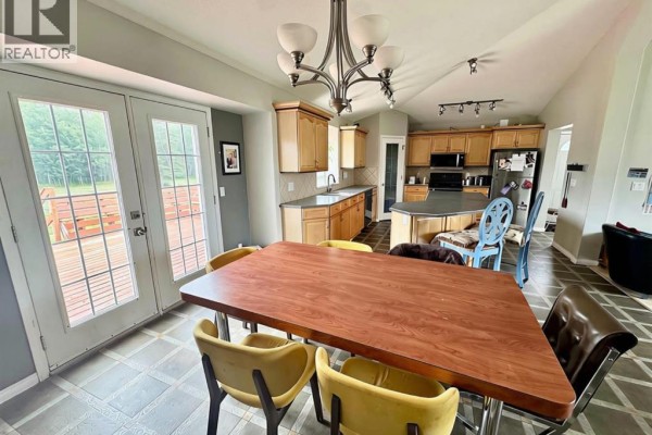 Open concept living and dining area with a kitchen island, dining table, and living room furniture. - 76317 Highway 49, Rural Smoky River No  130, M D  Of