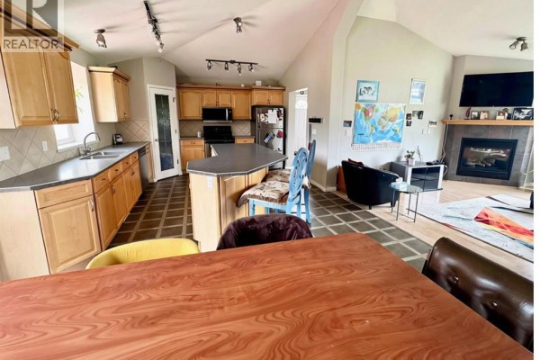 Living area with a fireplace, large windows with a view of the outdoors, and adjacent dining area. - 76317 Highway 49, Rural Smoky River No  130, M D  Of
