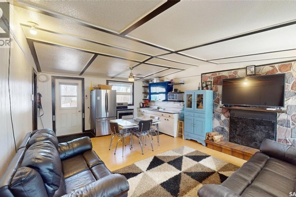 Living room with black leather sofas, a stone fireplace, a blue cabinet, and a dining area. - 764 Ennis Avenue, White Bear Ir 70