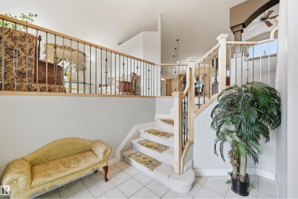 View of the foyer and staircase, featuring a decorative settee and potted plants. - 764 Haliburton Cr Nw, Edmonton