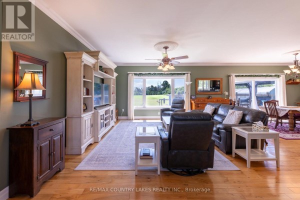 Living room with dark leather furniture, a large entertainment unit, and a wide window overlooking fields. - 764 Regional Road 12, Brock