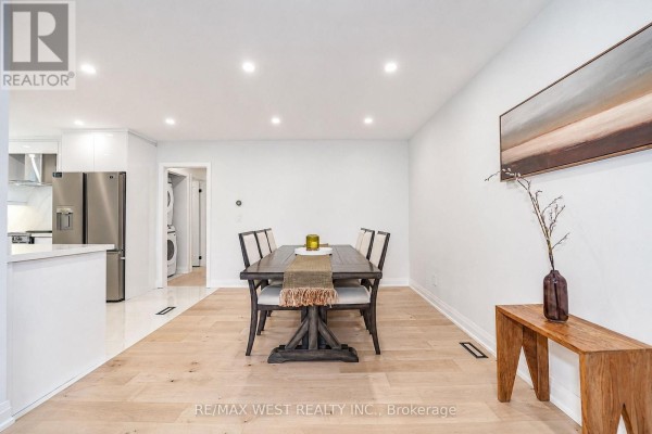 Dining area with a dark wood table, chairs, and a modern abstract artwork on the wall. - 765 Dodsworth Crescent, Mississauga