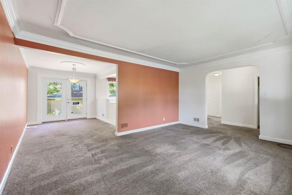 Living room with textured gray carpet, white ceiling, and archways leading to other rooms. - 765 Oakenwald Avenue, Winnipeg