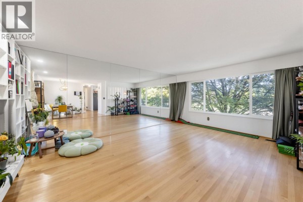 Interior view of a large, open room with hardwood floors, floor-to-ceiling mirrors, and large windows. - 7658 Fremlin Street, Vancouver