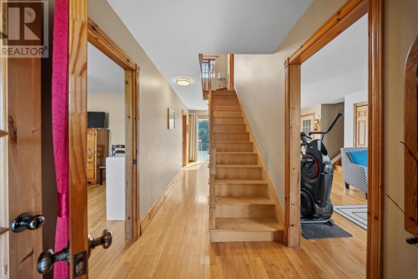 Interior hallway with wood floors, a staircase, and doorways to rooms. - 7678 Rte 12 Road, Ellerslie Bideford