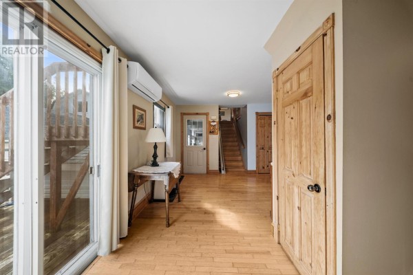 Interior hallway with wood floors, a sliding glass door, and a wooden door. - 7678 Rte 12 Road, Ellerslie Bideford