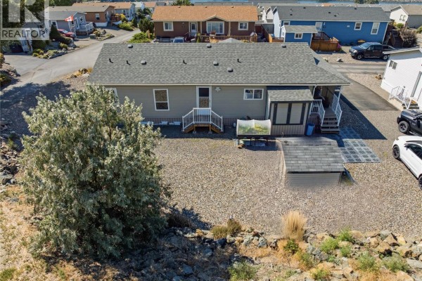 Aerial view of a light gray mobile home with a gravel yard and surrounding homes. - 768 Shuswap  E Road Unit# 24, Kamloops