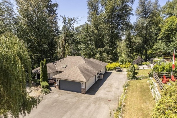 Aerial view of the house, garage, and surrounding wooded property. - 7681 Horne Street, Mission