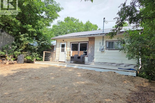Side view of the beige cottage showing a deck and surrounding trees. - 769 Ennis Avenue, White Bear Ir 70