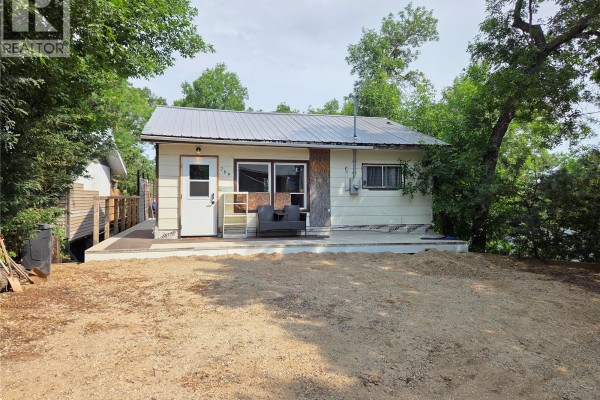 View of the beige cottage from the side, with a deck and landscaped area. - 769 Ennis Avenue, White Bear Ir 70