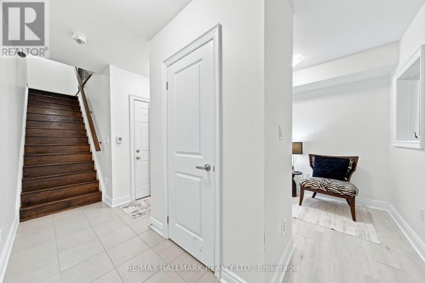 Interior foyer with tile flooring, wooden staircase, and doors to rooms. - 77 - 250 Royalton Common, Oakville