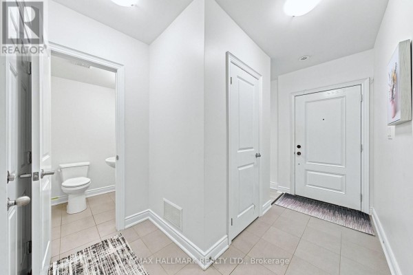 Foyer showing beige tile floor, white doors, and access to a powder room. - 77 - 250 Royalton Common, Oakville
