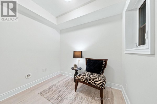 Small room with light wood flooring, chair, table, lamp, and decorative rug. - 77 - 250 Royalton Common, Oakville