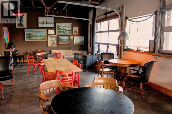 Interior dining area with tables, chairs, and artwork on the walls. - 77 8th Avenue, Lillooet