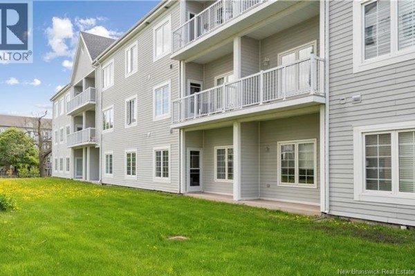 Close-up exterior shot of the building facade with '77 Cambridge Estates Condominiums' sign and stone and vinyl siding. - 77 Cameron Street Unit# 305, Moncton