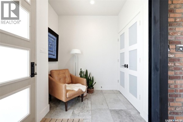 Entryway with a tan leather armchair, floor lamp, and frosted glass doors. - 77 Deer Foot Trail, Lumsden Rm No  189