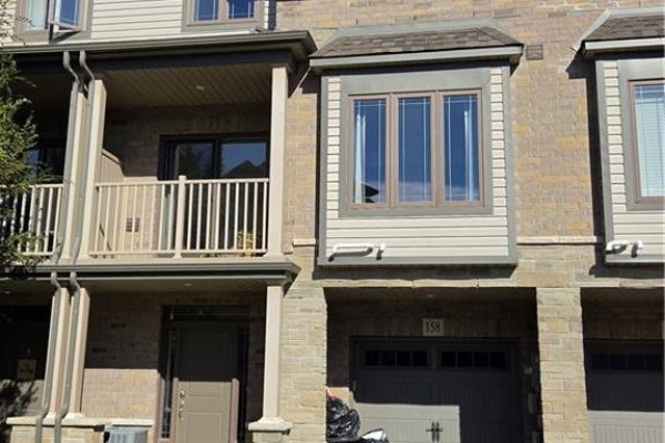 Close-up of townhouse unit 158, showing entrance, balcony, bay window, and stone facade. - 77 Diana Avenue Unit# 158, Brantford