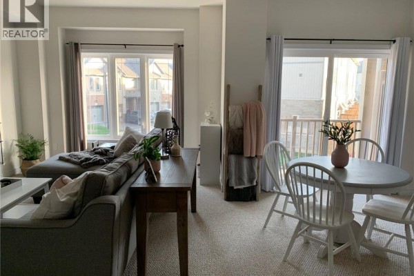 Living room with a grey sectional sofa, a round dining table, and large windows with blinds. - 77 Diana Avenue Unit# 158, Brantford