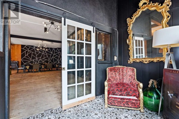 Interior view of a commercial space with a sliding barn door, seating area, and ornate mirror. - 77 East Main Street S, Welland